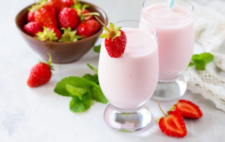 Two glasses of a strawberry milkshake made using dairy products