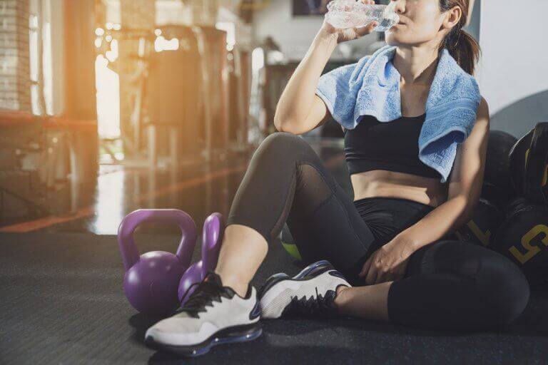 A woman drinking water after her workout to get a flat belly