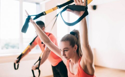 Woman doing chest press at the gym with trx straps
