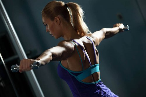 Woman in gym works her back with a machine