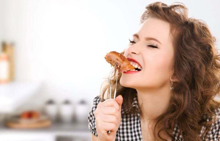 A woman biting into a piece of meat