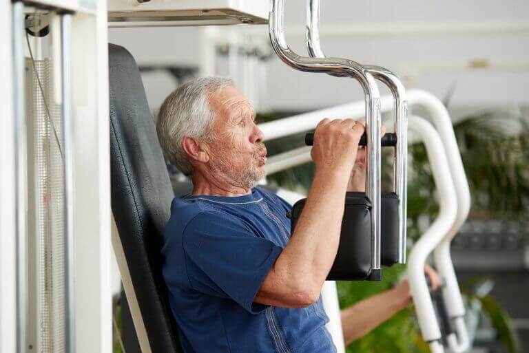 Old man working on his muscle strength at the gym