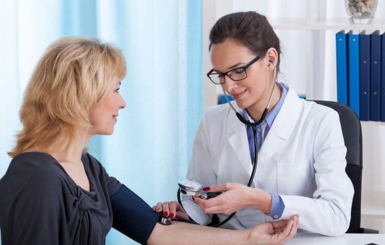 A doctor checking the blood pressure of an older woman