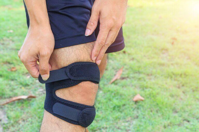 A man adjusting his knee brace to ensure a proper recovery of his dislocated kneecap