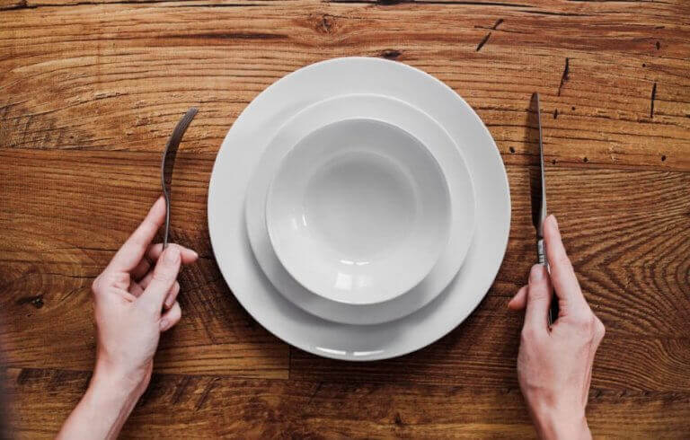 A person in front of an empty plate to simbolize long periods of fasting before doing sports