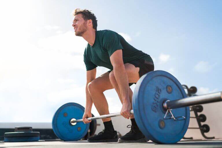 A man lifting deadweight to support the text describing this workout for back muscle strength.