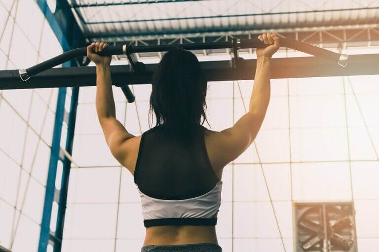 A woman doing pull ups for back muscle strength