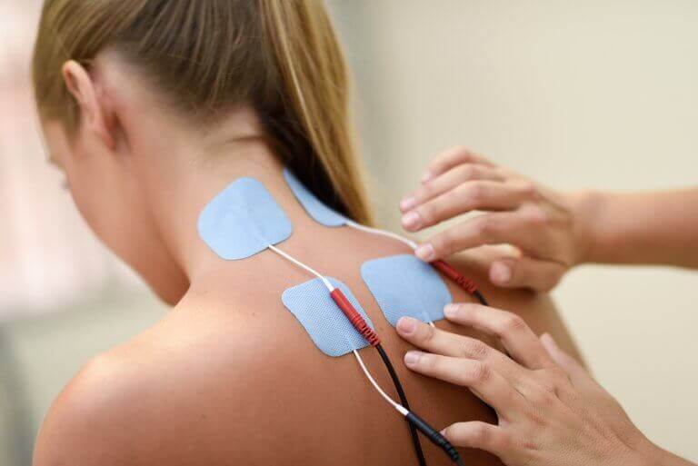 Photo of a woman having electrodes applied to her back, as described in the text to show electrotherapy benefits