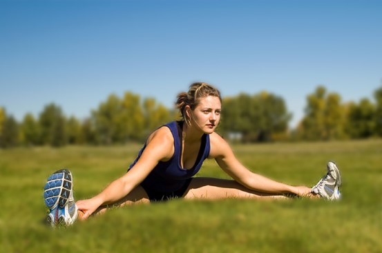 A woman doing stretches for her adductor muscles outside