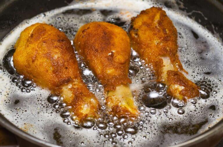 Chicken legs frying in fat.