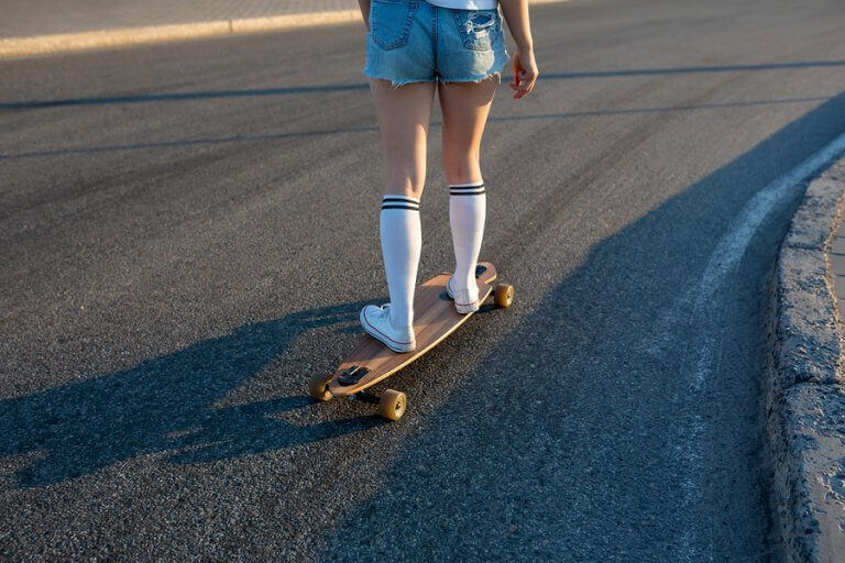 A girl riding a longboard downhill