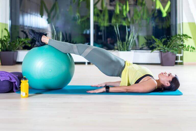 A woman training with a fit ball at her home