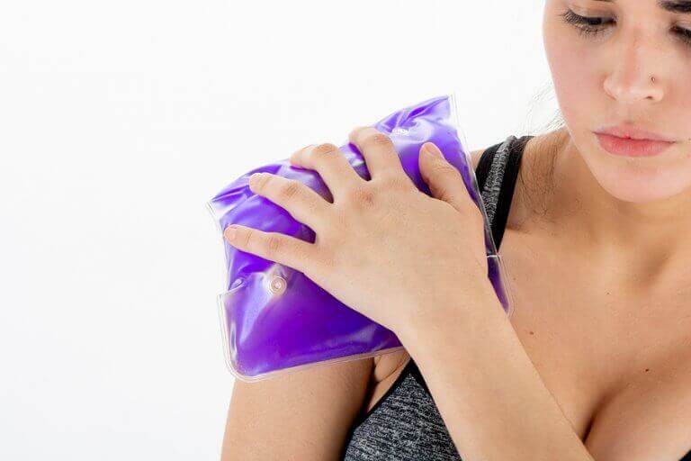 A woman applying a heat or cold pack to a shoulder injury