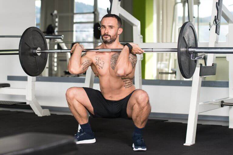 A man doign barbell squats as part of his strength training program for cycling