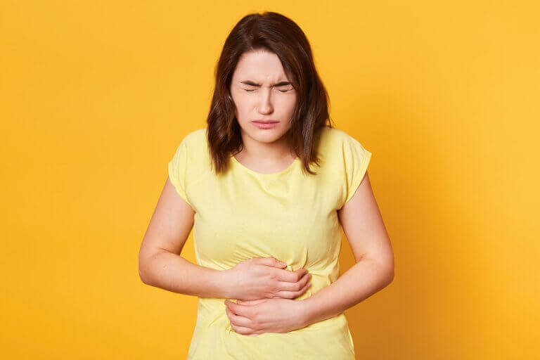 Photo of a girl holding her stomach, dealing with digestive problems. 