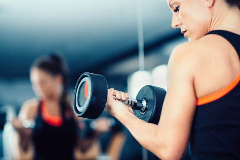 A woman lifting weights in a gym who may have vigorexia disorder