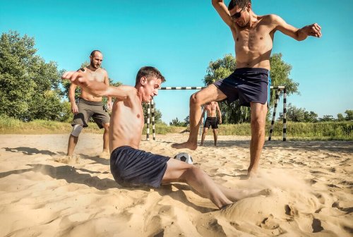 Men playing beach soccer which is one of the fun beach sports in this article.