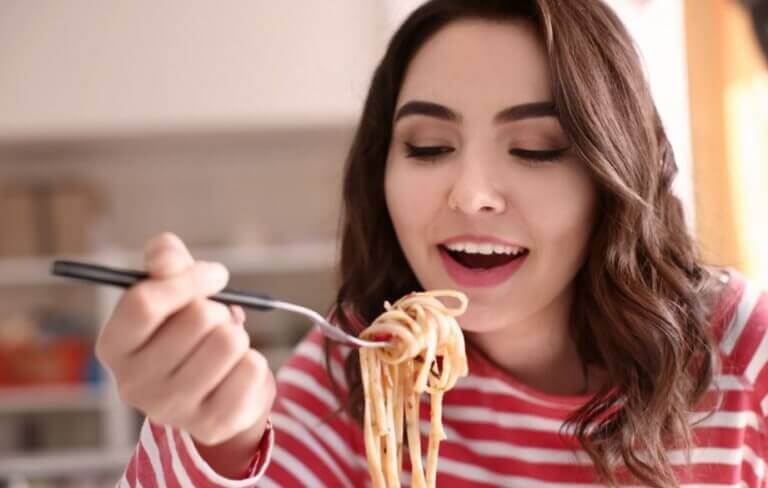 A woman eating whole wheat pasta as a carb option to gain muscle