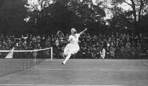 Suzzane Lenglen, playing tennis, one of the first women tennis players, supports text.