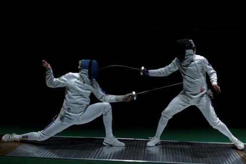 Two people engaged in a fencing match.