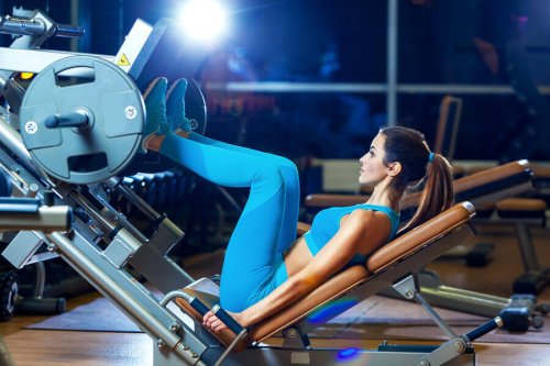 A woman using a squat machine.