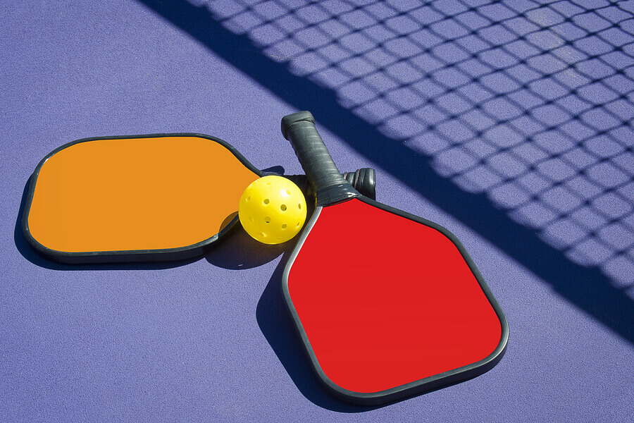 Paddles and ball on a pickleball court.