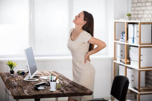 A woman suffering from back pain due to a poor posture when sitting down at work