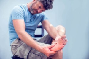 A man massaging a painful cramp in his foot.