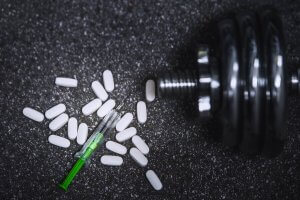 A dumbbell with pills and a syringe.