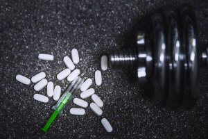 A dumbbell with pills and a syringe. 