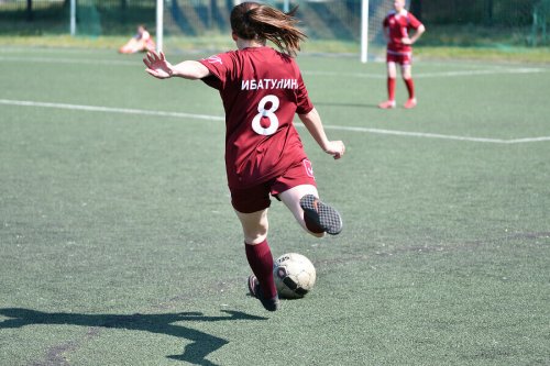 A girl kicking a soccer ball.
