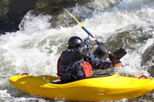 Man in a yellow kayak in the rapids to sport description in text for canoeing.