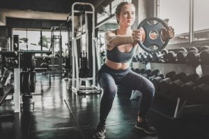 A woman doing squats with a weight in the gym.