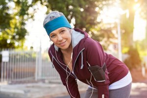 A woman taking a break from running outdoors.