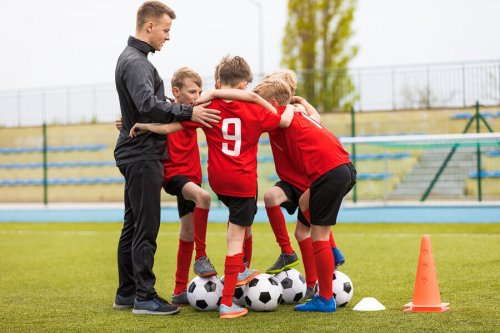 A coach encouraging teamwork in his soccer players.