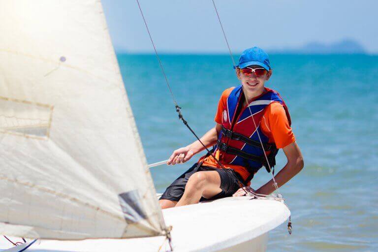 A young boy steering a sailboat durign a regatta