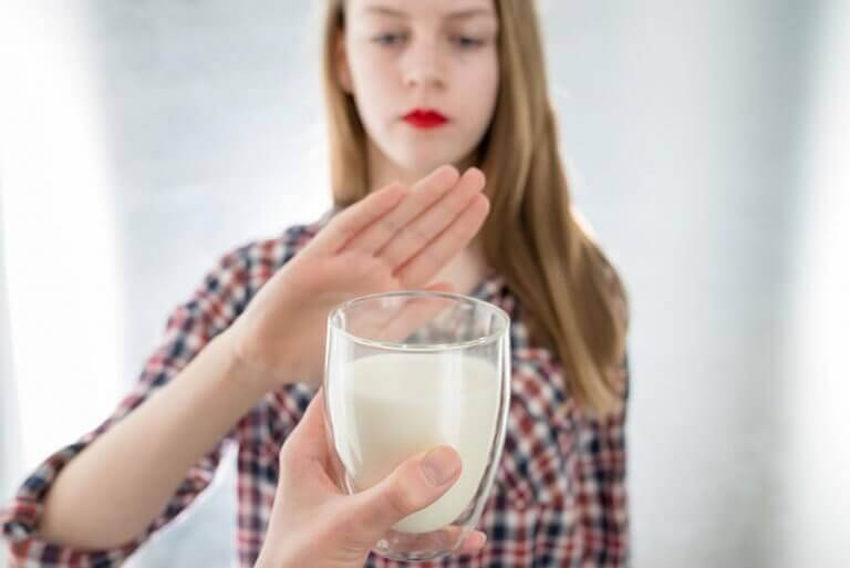 Woman saying no to a glass of milk because she is lactose intolerant