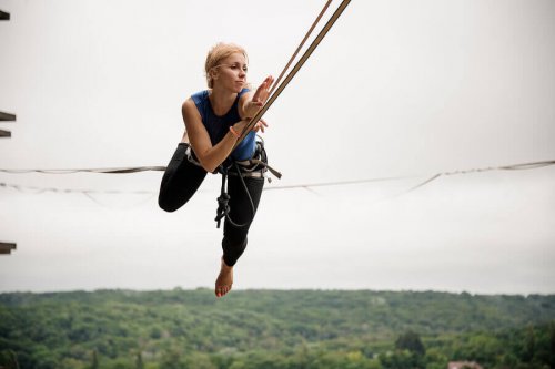 A woman with a harness doing slackline.
