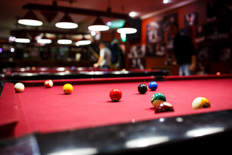 A billiards table with people playing in the background