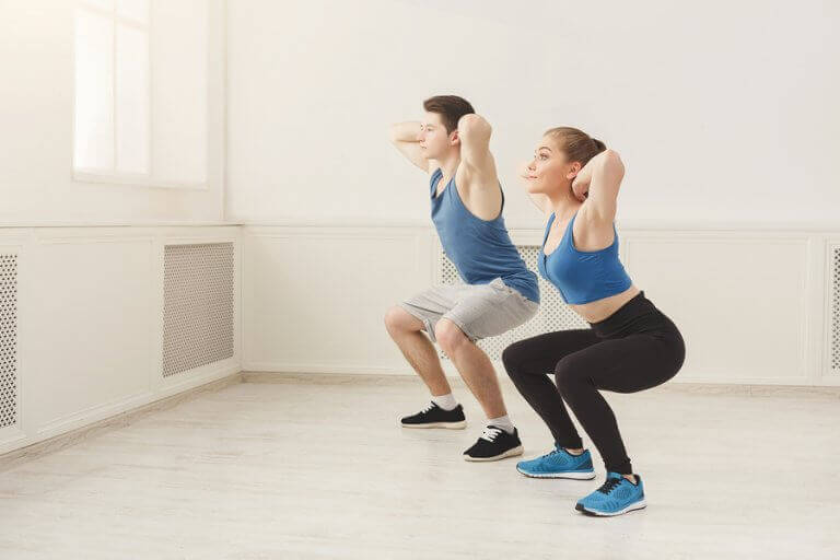 A man and a woman doing squats inside their home