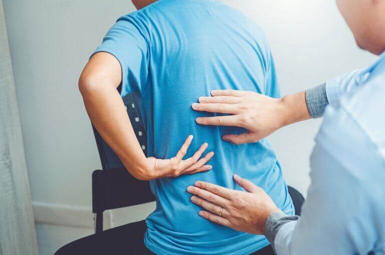 A doctor checking the back of a patient to detect herniated disks