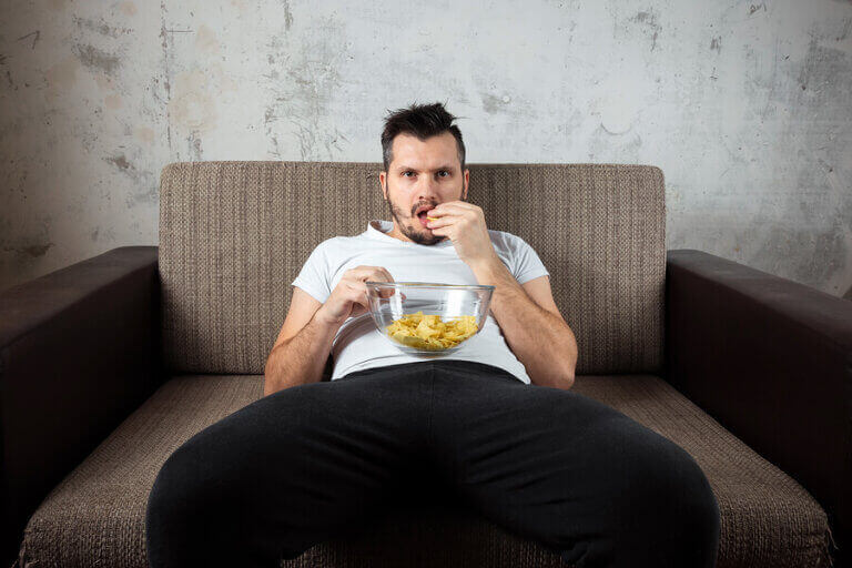 A man eating chips and having a sedentary lifestyle due to the coronavirus isolation