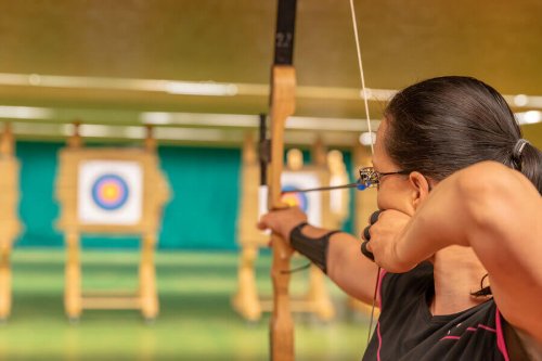 A woman doing indoor archery.