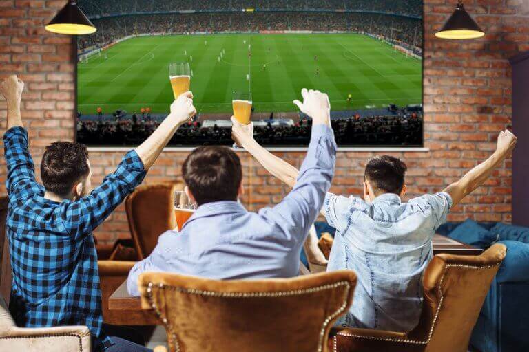 A group of three men watchin a sports event on TV