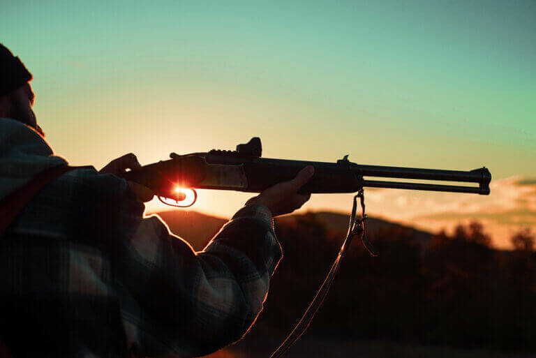 A man hunting during the sunset while following the proper legal regulations of sport hunting