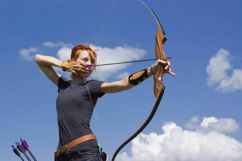 A woman aiming with a bow and arrow.