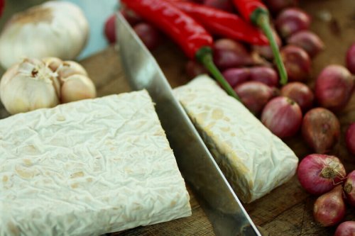 A knife cutting a slice of tempeh.