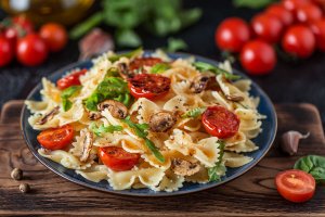 A pasta plate with tomato and basil.