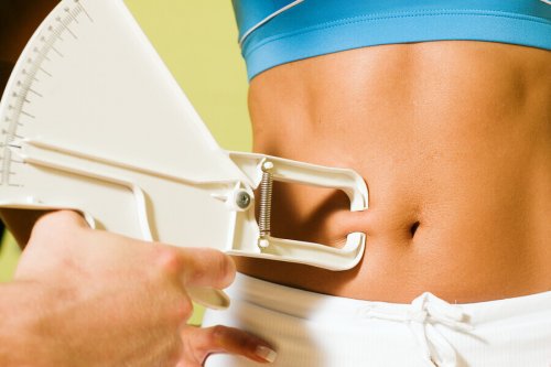 Girl makes measurements to assess fat loss burn abdominal fat
