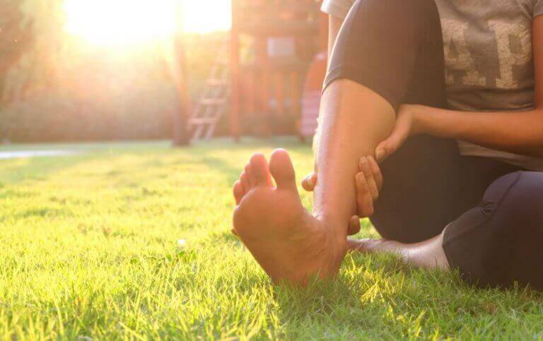 A woman holding her foot to ease the pain caused by a heel spur